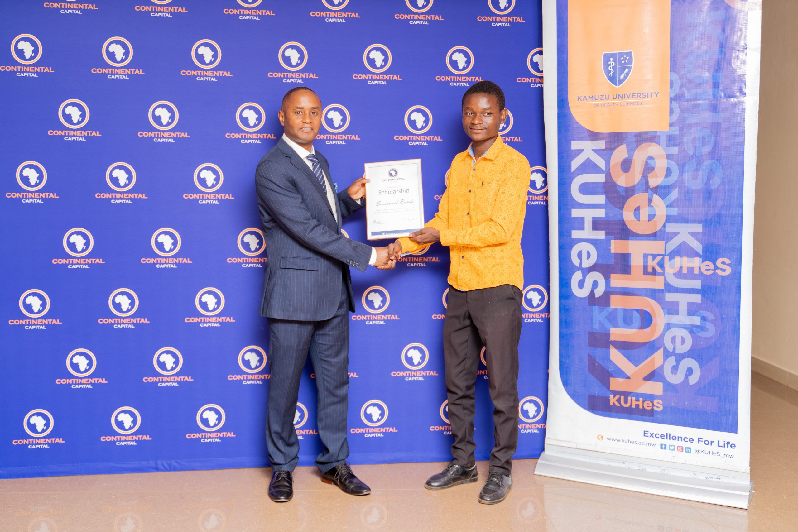 Kenneth Mmadi (left), General Manager of Continental Capital Limited, presents a symbolic scholarship award to Emmanuel Banda